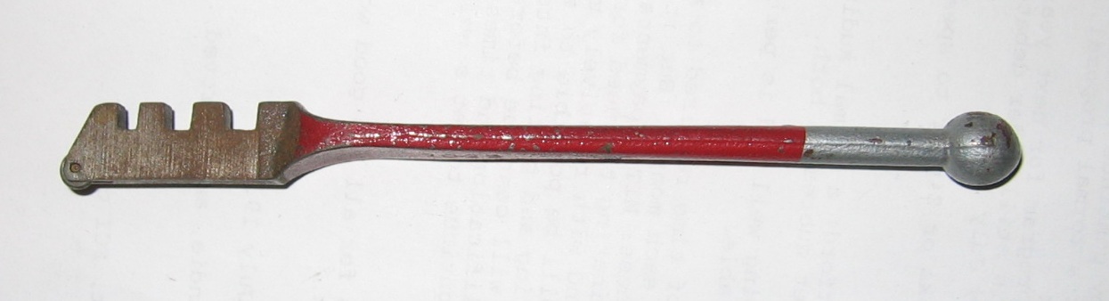 A glass cutter — the hardened cutting wheel (top), notches for snapping the break, and the heavy ball on the handle used for tapping the score