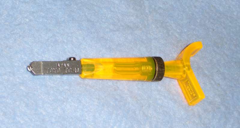 An oil-guided glass cutter — the hollow handle is an oil tank that feeds the wheel as you score, keeping every line lubricated